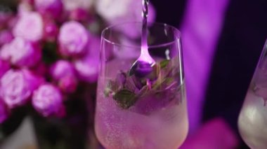 Barmen bardakta alkollü kokteyl ve nane ve buz karıştırıyor.