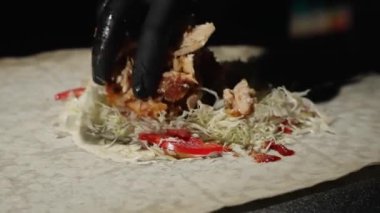 Restoranda Pita ekmeğinde et şavurması pişirmek. Siyah eldivenli erkekler et ve taze sebzeleri Pita ekmeğine döker. Beslenme kavramı