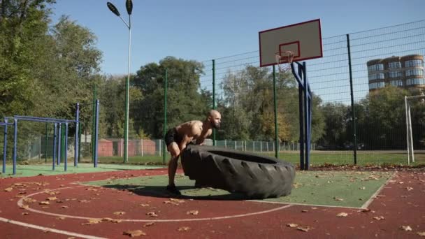 肌肉发达的运动员在运动场上以慢动作举起一个巨大的轮子 摔跤运动员的力量和耐力训练 — 图库视频影像