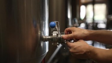 Man working at a brewery closing one of the distillery stills.