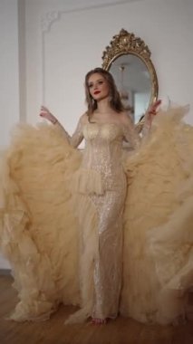 Lüks elbiseli ve parlak makyajlı hoş bir genç kız evin içinde bir aynanın yanında duruyor.