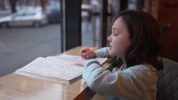 Anaokulu Çağındaki Bir Kız Pencerenin Kenarında Oturur Renkli Bir Kalemle — Stok video