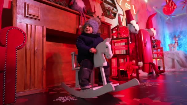 Маленький Мальчик Качается Игрушечной Деревянной Лошади Резиденции Деда Мороза Волшебной — стоковое видео