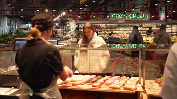お店の営業コンサルタントが甘い釉ドーナツについてお客様に伝えます — ストック動画