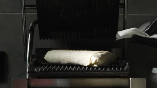 調理人の手は フライパンのための加熱グリルにピタパンにケバブロールを反転 シャワルマの準備の段階 ファーストフード店 — ストック動画
