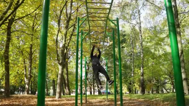 Мужчина Поднимается Горизонтальной Лестнице Атлетик Мускулистым Телом Тренируется Парке Открытом — стоковое видео