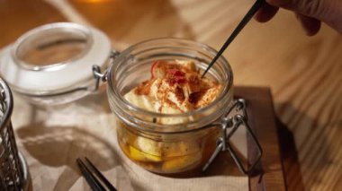 Delicious pieces of cheese marinated in hot spices are served in a glass jar in the restaurant.