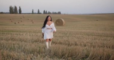 A girl in a white dress is walking along the mowed field