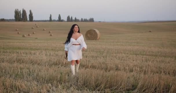 Seorang Gadis Dengan Gaun Putih Berjalan Sepanjang Lapangan Dipangkas — Stok Video