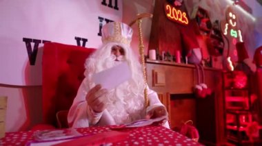 Santa Claus reads letters with childrens wishes in his fairy-tale residence