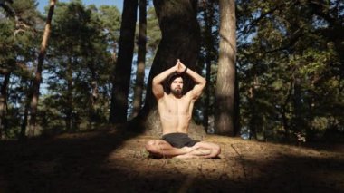 A young athlete practices yoga and meditation while improving his body in nature