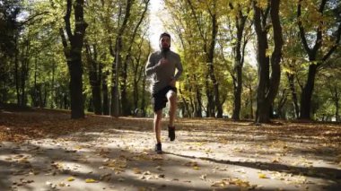 A young athlete is doing warm-up before training in an autumn park