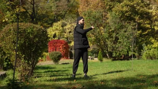 秋の公園で男が暖を取っている スポーツ 健康的なライフスタイル 物理的なトレーニング — ストック動画