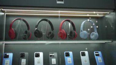Headphones and smartphones of various models are on sale in the shop window