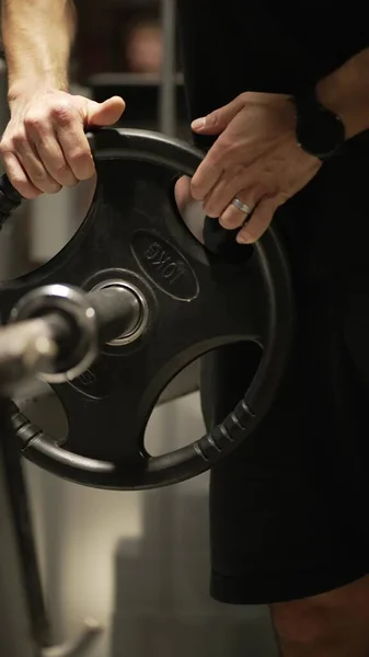 The athlete adds weights to the barbell between sets of the chest press.