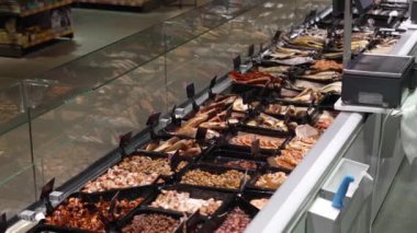 A variety of seafood is displayed on the counter of the store. Smoked, baked, salted, stewed fish are available for customers to choose from in the store.