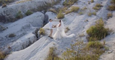 The bride tenderly embraces her groom while standing on a high mountain. Wedding ceremony