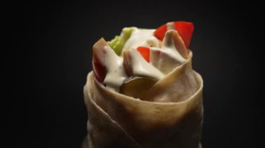 Pieces of chicken in pita bread with vegetables and greens covered with a delicious sauce close-up.