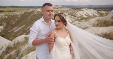 Yeni evliler, neşeli gelin ve damat dağ yamacında yürüyor. Düğün çifti. Mutlu bir aile. Aşık bir adam ve kadın. Şık bir gelinlik içindeki gelin. Yavaş çekim
