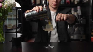 Bartender Making a fancy Margarita. Bartender Pouring Cocktail from Shaker to Glass