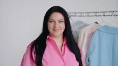 Fashion, retail. A satisfied woman smiles at the camera in a clothing boutique