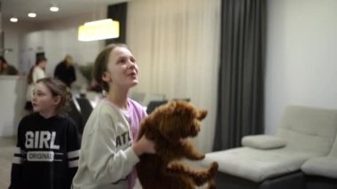 Children play with a small pet at home in the kitchen