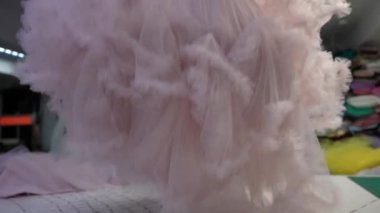 A woman designing wedding dresses lays out individual details on a table in a sewing shop