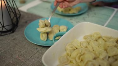 The female hands of the hostess put hot dumplings on the plates