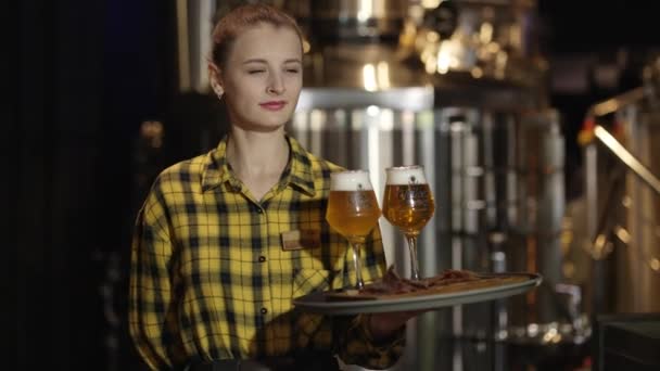 魅力的な若い女の子のウエイターは トレイにビールとメガネを運ぶ ウエイターはパブでビールを提供します — ストック動画