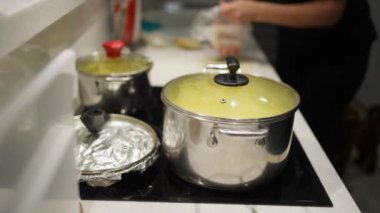 The woman has put an iron pan on the stove and is preparing a delicious and appetizing dinner for the whole family. Slow motion.