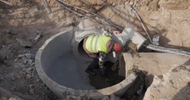 Ferroconcrete. A worker concretes a pipe, pours cement mortar into sewer pipes