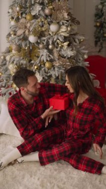 A man in love gives his wife a gift for her birthday, New Years Day or wedding anniversary. The woman is happy with the gift.