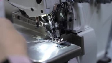 Seamstress sews on a sewing machine close-up of female hands.