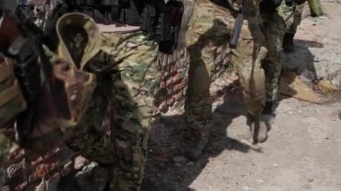 A group of elite forces fighters, a tactical unit, members of a reconnaissance group in camouflage uniforms, walk in line, carrying weapons