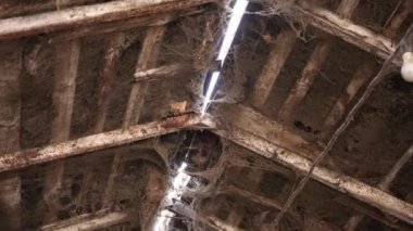 The old broken and cracked rusty roof in the building and all covered with cobwebs