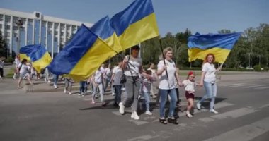 Children and adults carry the flag of Ukraine and sing the national anthem in support of the fight against the invaders