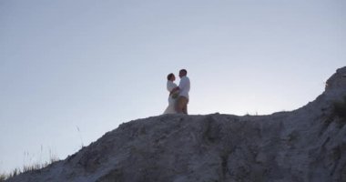 The bride tenderly embraces her groom while standing on a high mountain. Wedding ceremony