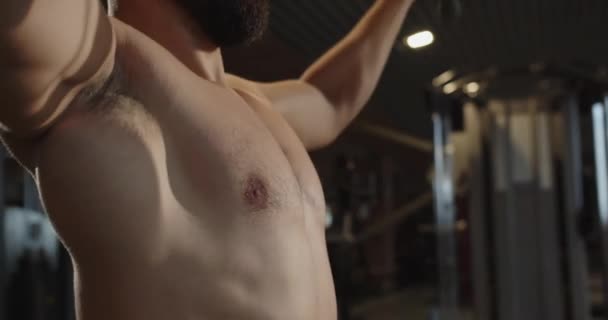땀으로 얼굴을 감싸고 근육질의 남자가 기구에 무거운 근육을 훈련시키고 있습니다 — 비디오