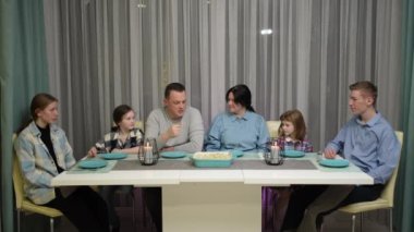 Lezzetli yemeklerle dolu büyük beyaz bir masada güzel bir aile toplantısının portresi.