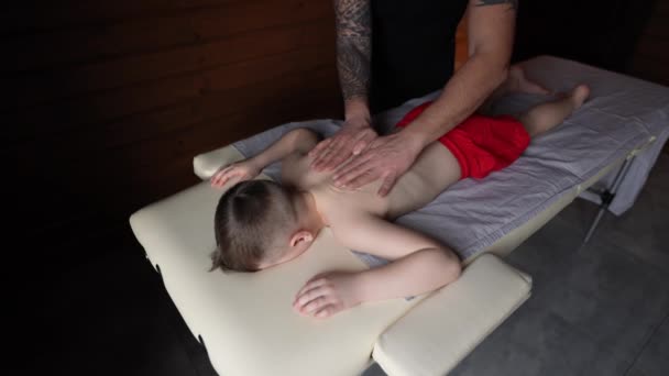 Masér Fyzioterapeut Poskytuje Terapeutickou Relaxační Masáž Malému Chlapci Ležícímu Masážní — Stock video