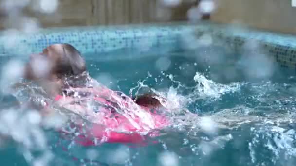一个穿着粉色泳衣的可爱小女孩在游泳池里游泳 — 图库视频影像