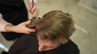 Kuaför şık bir saç modeli bir erkek müşteri için yapar.