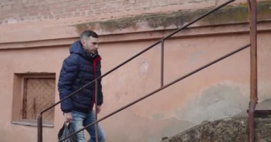 Adam eve gider ve apartmanın eski püskü girişine girer.