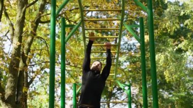 Sırt kaslarını şişiren güçlü atletik yakışıklı bir adam. Fitness adamı barfiks egzersizi yapıyor.