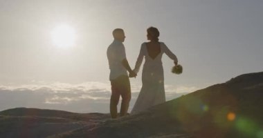 Neşeli adam ve kadın dışarıda yürüyor. Mutlu bir çift dağlarda fotoğraf çekiyor. Gelin ve damat düğünlerini dağlarda kutluyorlar..
