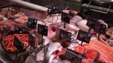 Süpermarketin vitrininde buzun üzerinde bir sürü taze deniz balığı yatıyor. Dükkanda satılığa çıkarılmış bir sürü çiğ donmuş deniz balığı var.