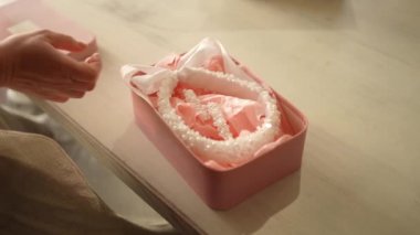 Bir kadın inci mücevherleri bir kutuya koyar.