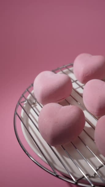 ピンクのアイシングで覆われた甘いハート型のデザートは ピンクの背景にトレイを回転させます 菓子類 — ストック動画