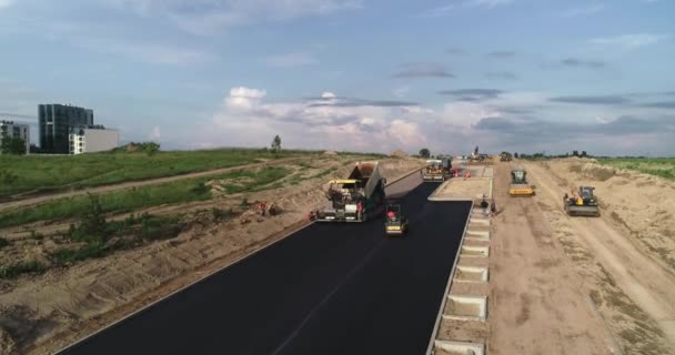建造一个新的沥青交叉口 修建一条沥青路面和一个交叉口 在沥青路面未完工的路段上矗立着许多设备 — 图库视频影像