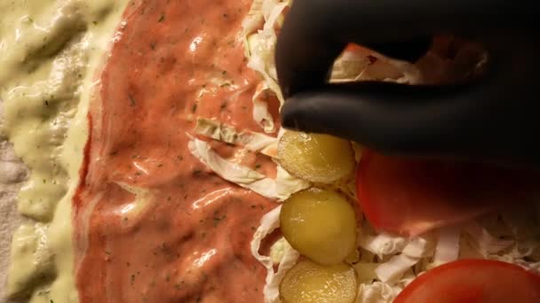 ファーストフードレストランの黒い手袋で手 シェフは ピタパンにドナーケバブのための成分を置きます 野菜やハーブを追加 肉やキャベツ トマト キュウリやホットソース — ストック動画